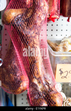 Un grande osso affumicato in una borsa a rete. Cane tratta in vendita nel negozio di animali. Foto Stock