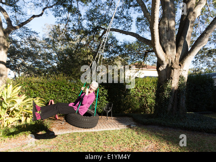 Felice donna matura giocando su un pneumatico Swing, STATI UNITI D'AMERICA Foto Stock