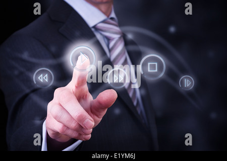 Un uomo premendo un pulsante su un display digitale per il controllo dei media digitali, musica e film. Foto Stock