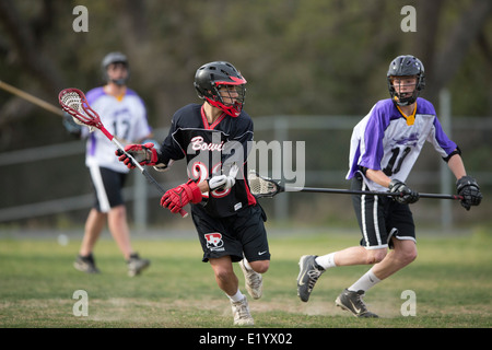 Alta scuola ragazzi indossare i caschi e di gareggiare in una gamma lacrosse corrispondono a Austin, Texas. Foto Stock