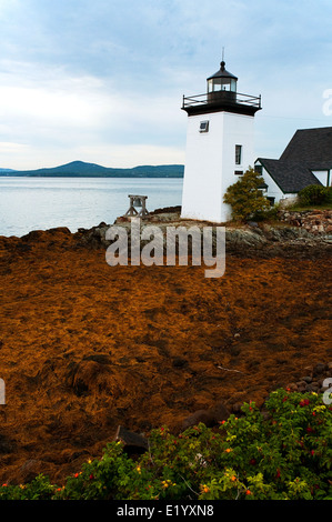 Sun si rompe attraverso le nuvole da Grindle Point lighthouse a bassa marea su Islesboro isola, nel Maine. Foto Stock