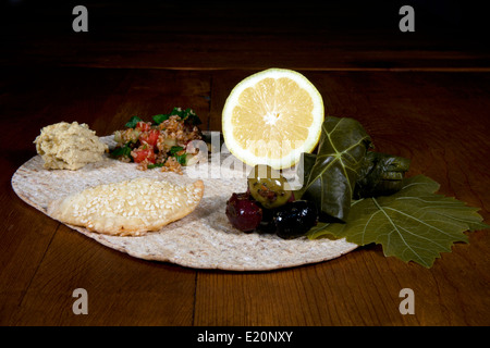 In Medio Oriente la diffusione di antipasti tra cui tabulé, hummus, dolma, fatayees e speziato olive su una tavola di legno Foto Stock