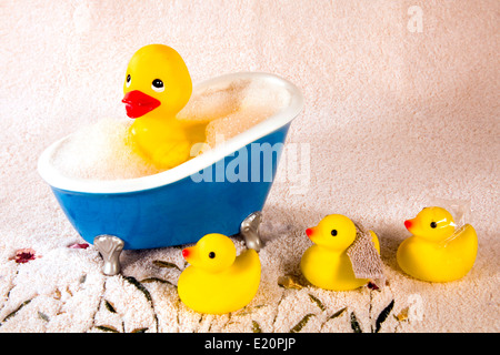 Gomma grande duckie in bolla bagno con tre piccole anatre in attesa su un tessuto spugna asciugamano. Foto Stock