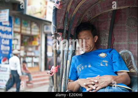 Maschio driver rickshaw dormire al lavoro a Kathmandu in Nepal Foto Stock