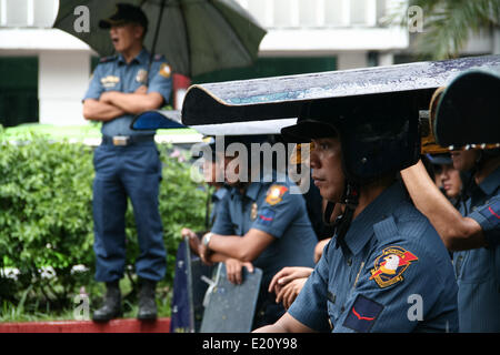 Manila, Filippine. 12 Giugno, 2014. Gli ufficiali di polizia utilizzano i loro scudi contro un improvviso acquazzone mentre in guardia contro i dimostranti tenendo un programma a Kalaw Avenue a Manila. Diverse centinaia di manifestanti hanno tenuto diverse manifestazioni di protesta in tutto Metro Manila la marcatura del Filippine " 116Giorno di Indipendenza. Diversi gruppi chiamati per la responsabilità e la trasparenza in merito agli scandali di corruzione di alti funzionari del governo. I manifestanti hanno anche chiesto la cacciata del Presidente Aquino per il suo presunto incompetency nel governare la sua amministrazione. Credito: PACIFIC PRESS/Alamy Live News Foto Stock