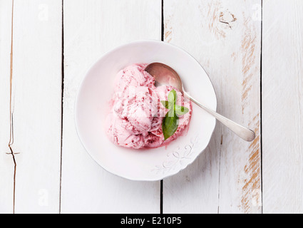 Gelato alla fragola con il verde del basilico in vaschetta sul bianco sullo sfondo di legno Foto Stock