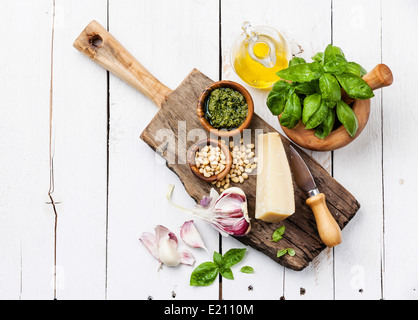 Ingredienti per preparare il pesto in un mortaio in bianco sullo sfondo di legno Foto Stock