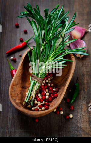 Le spezie (peperoncino, rosmarino e aglio) su un tavolo di legno Foto Stock