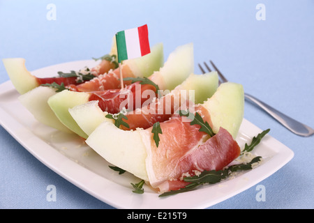 Mature fette di melone con prosciutto, parmigiano sulla piastra bianca Foto Stock