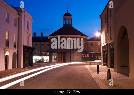 Poundbury. Il principe Charles' esperimento nella moderna pianificazione urbana. Fari di automobile passato streak Buttercross Square. Il Dorset, Inghilterra, Regno Unito. Foto Stock