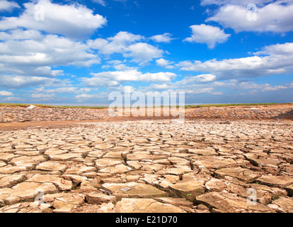 Siccità terreno contro un cielo blu con nuvole Foto Stock