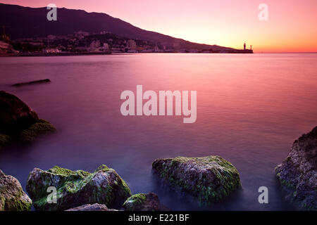 Spiaggia rocciosa tramonto sul mare Foto Stock