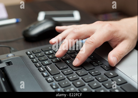 Mano dell'uomo bianco premendo il tasto di invio sulla tastiera del notebook Foto Stock