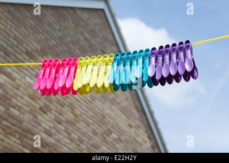 Multi colore pioli di plastica appeso su una linea di lavaggio Foto Stock