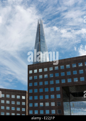 Ampia angolazione del London Shard con ufficio blocchi con sky quadrato pieno di finestre in primo piano contro il blu e il cielo bianco Foto Stock