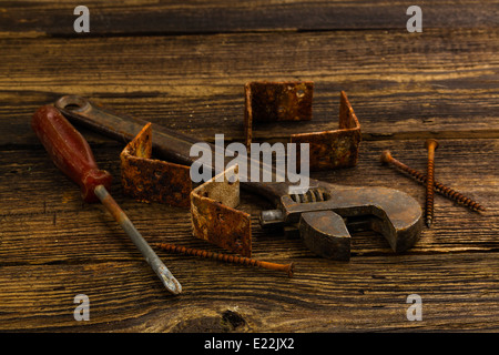 Angolo tiranti, viti, un cacciavite e una chiave regolabile su sfondo di legno Foto Stock