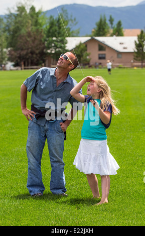 Padre e figlia giovane volare un aquilone su un campo erboso Foto Stock