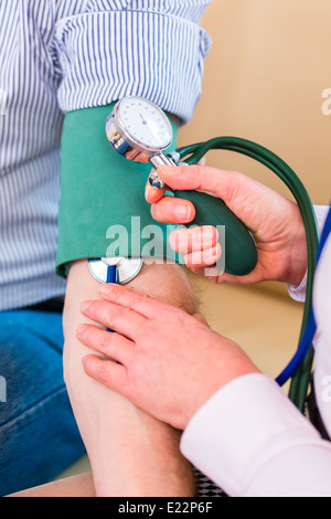 Donna controllando la pressione del sangue con uno stetoscopio e del manicotto sul braccio dell'uomo Foto Stock