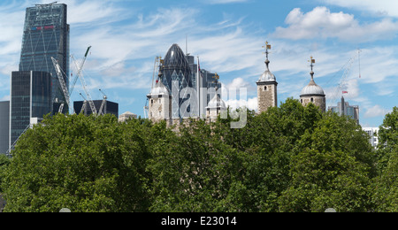 Parte della Torre di Londra con edifici moderni in background compreso il cetriolino e alberi in primo piano Foto Stock