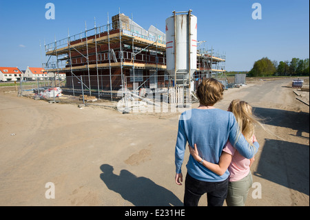 Coppia giovane cerca sul sito in costruzione come la loro nuova casa è in fase di costruzione Foto Stock