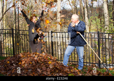 Uomo e donna che gioca in foglie di autunno Foto Stock