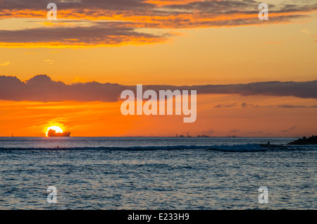 Barca profilarsi davanti al tramonto visto da Waikiki Beach in Hawaii Foto Stock