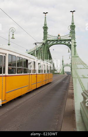 Tram giallo attraversando il Ponte della Libertà a Budapest, Ungheria Foto Stock