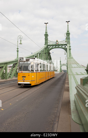 Tram giallo attraversando il Ponte della Libertà a Budapest, Ungheria Foto Stock