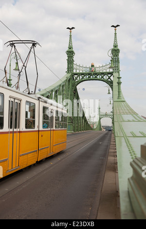 Tram giallo attraversando il Ponte della Libertà a Budapest, Ungheria Foto Stock