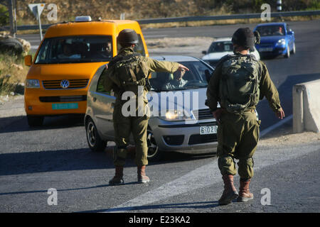 Hebron, West Bank. Il 15 giugno, 2014. Soldati israeliani bloccare una strada durante una operazione militare per cercare tre mancano giovani israeliani vicino al West Bank città di Hebron, il 15 giugno 2014. Il Primo Ministro israeliano Benjamin Netanyahu ha detto che i giovani ebrei erano stati rapiti nella West Bank da parte di un'organizzazione terroristica. Credito: Mamoun Wazwaz/Xinhua/Alamy Live News Foto Stock