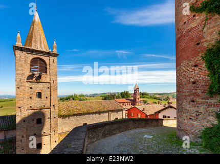 Campanile medievale e un muro di mattoni sotto il cielo blu nella piccola città di Serralunga d'Alba in Piemonte, Italia settentrionale. Foto Stock