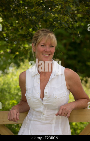 Ritratto di una donna in abiti estivi appoggiato su di una recinzione in campagna Foto Stock