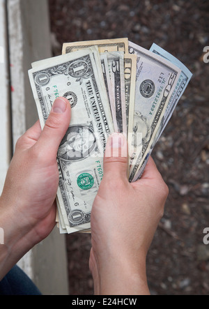 Una persona che tiene il conteggio e il dollaro americano note. Foto Stock