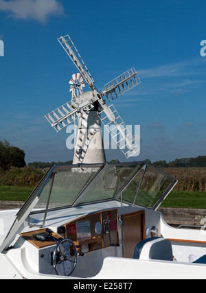 La crociera barca ormeggiata su Thurne Dyke, con mulino di drenaggio al di là, Thurne, Norfolk, Inghilterra Foto Stock