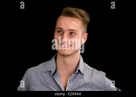 Attraente bionda, blue eyed giovane uomo sorridente e guardando lontano, isolato Foto Stock