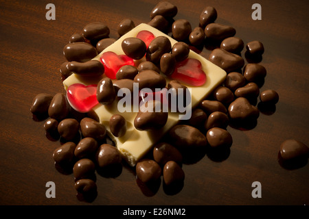 Una miscela di pezzi a nido d'ape, rivestite di cioccolato al latte e cioccolato bianco bar, embedded con gelatina rossa cuori. Foto Stock