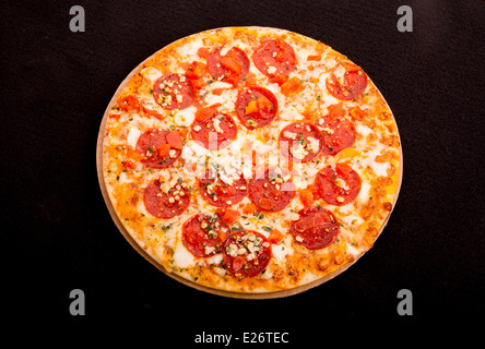 Un caldo cheesy salsiccia per pizza pizza su sfondo nero Foto Stock
