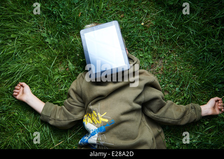 Bambino biondo giovane ragazzo giocando con una tavoletta digitale computer pc all'aperto nel parco Foto Stock