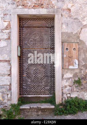 Una vecchia porta di legno con una scatola sulla parete accanto ad esso con una faccina sorridente sul Foto Stock