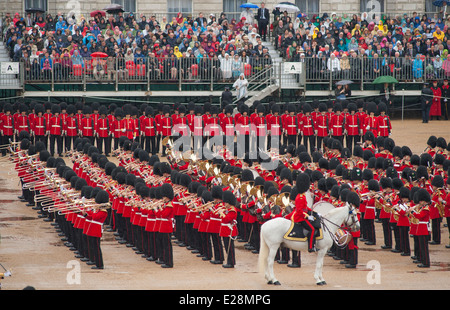 Ammassato bande delle guardie reggimenti giocando al colonnello della revisione, Trooping il colore, con gli spettatori a guardare sotto la pioggia Foto Stock