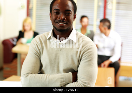 Ritratto di happy businessman africani in piedi di fronte ai colleghi in ufficio Foto Stock