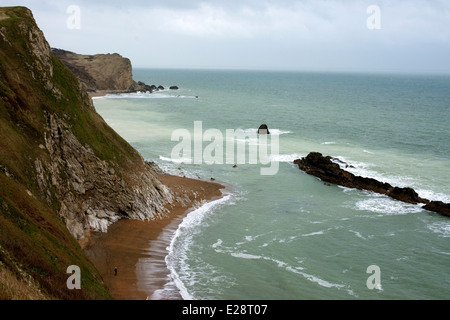 Il Dorset Crumple, la pietra di Portland 'man di guerra' pila in corrispondenza di Lulworth, Dorset con Chalk Cliffs, e un viandante sulla spiaggia al di sotto di Foto Stock