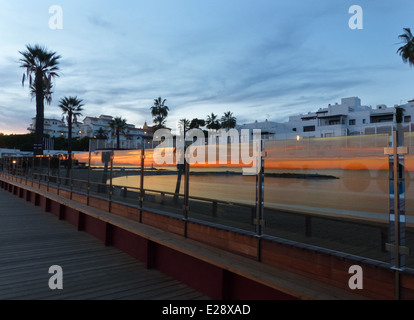 Una luce arancione brillante tramonto riflesso in uno schermo di vetro vicino alla spiaggia Foto Stock