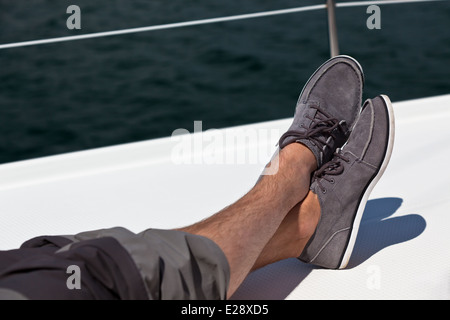 Una coppia di peloso le gambe dei pantaloni e topsiders su bianco yacht deck. Yachting Foto Stock