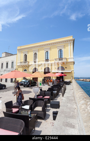 Ristorante esterno di tabelle in un giorno d'estate con cielo blu, rosso con ombrelloni, in Gallipoli, Puglia, Italia meridionale Foto Stock
