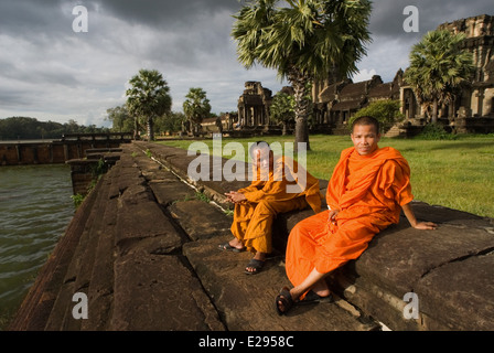 Due monaci buddisti all'esterno del tempio di Angkor Wat. Angkor Wat, la sua bellezza e il suo stato di conservazione è impareggiabile Foto Stock