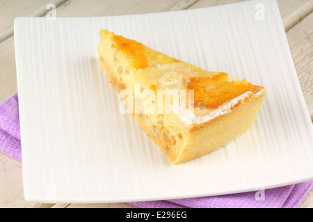 Una fetta di l'originale dolce pasquale da Napoli chiamato pastiera, servita su una porcellana bianca piatto su un sfondo di legno. Foto Stock