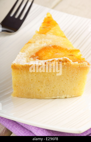 Una fetta di l'originale dolce pasquale da Napoli chiamato pastiera, servita su una porcellana bianca piatto su un sfondo di legno. Foto Stock