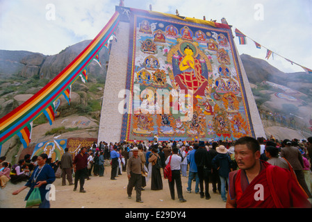 Un monaco tibetano passeggiate da un gigante 'Thangka", un dipinto o ricamato banner buddista al Monastero di Sera, Lhasa, in Tibet Foto Stock