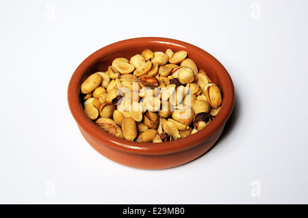 Salate dadi misti (nocciole, arachidi, pistacchi, mandorle) in un piatto di terracotta. Foto Stock